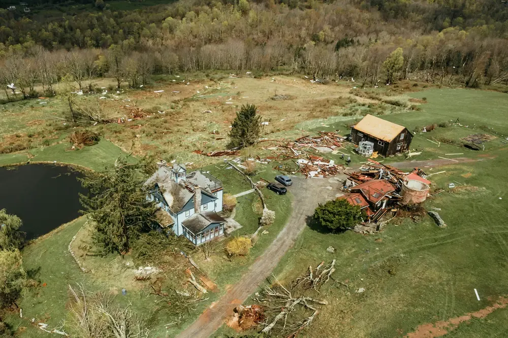 Aerial view of a storm-damaged property with debris spread across the surrounding ground