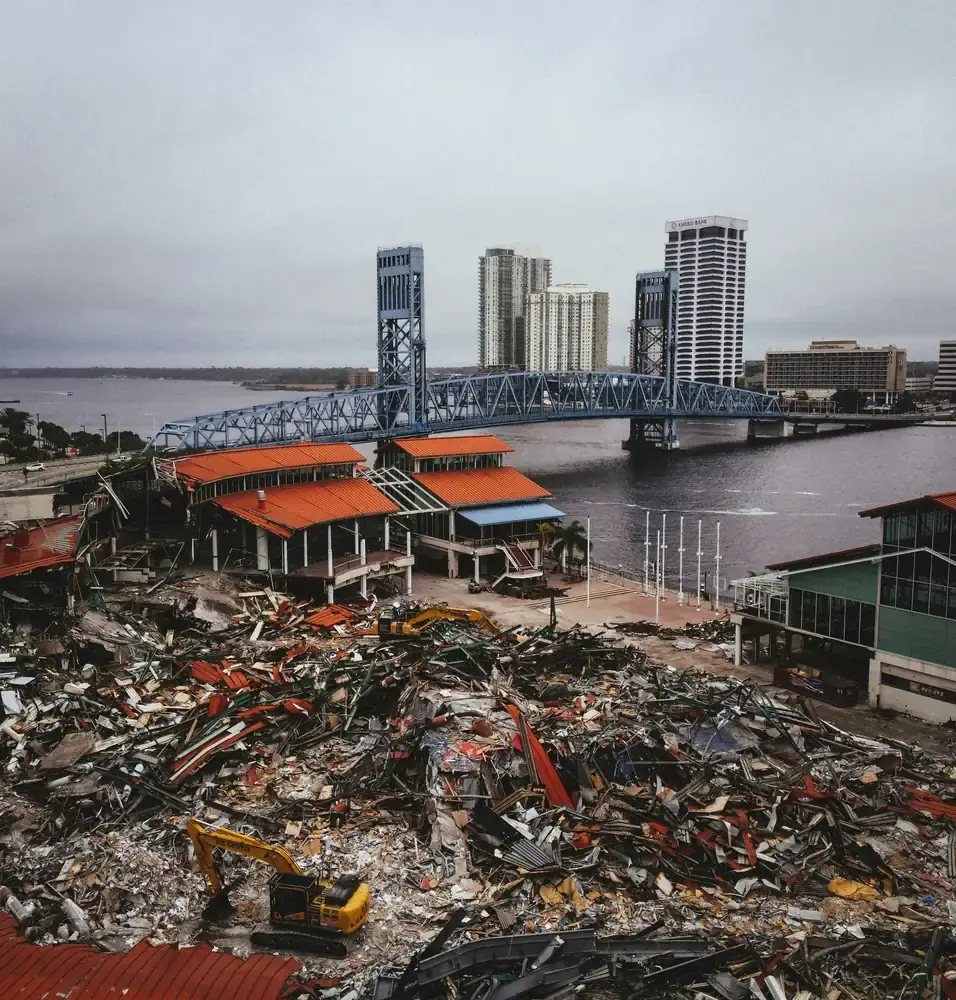 Aerial view of a large waterfront demolition with a debris field beside the water