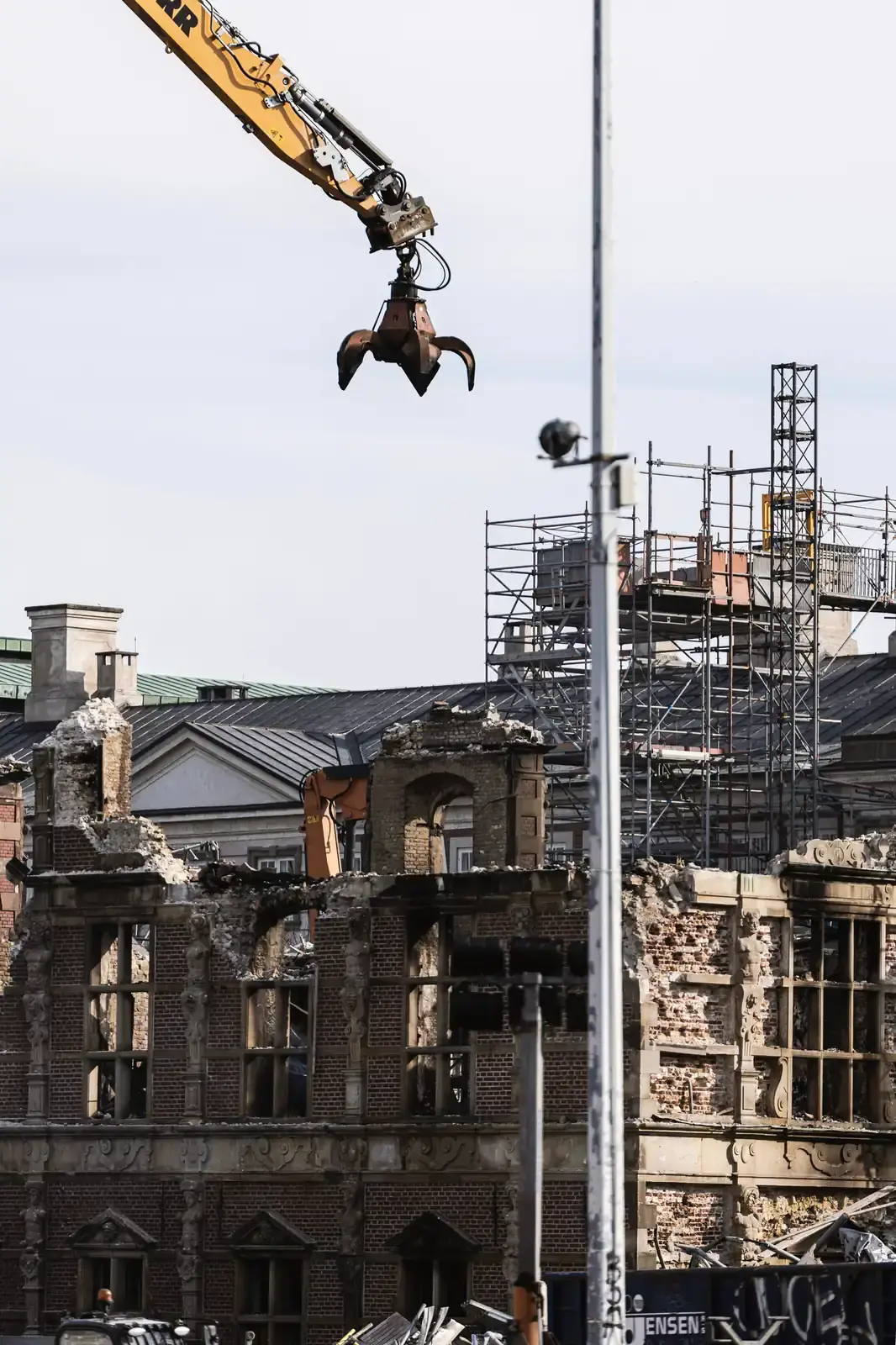 A grapple suspended above an ornate stone facade held up by scaffolding